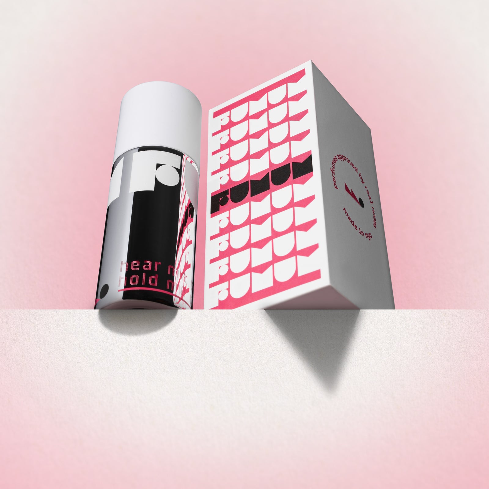 Perfume and box with 'Fumum' branding on a light pink background