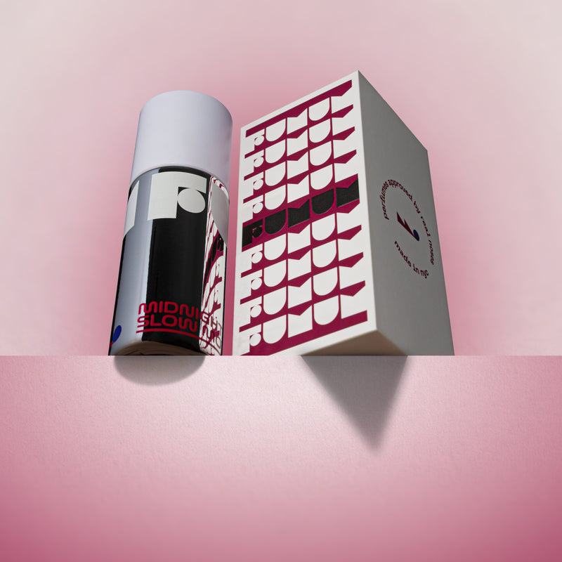 Perfume and box with 'Fumum' branding on a pink background