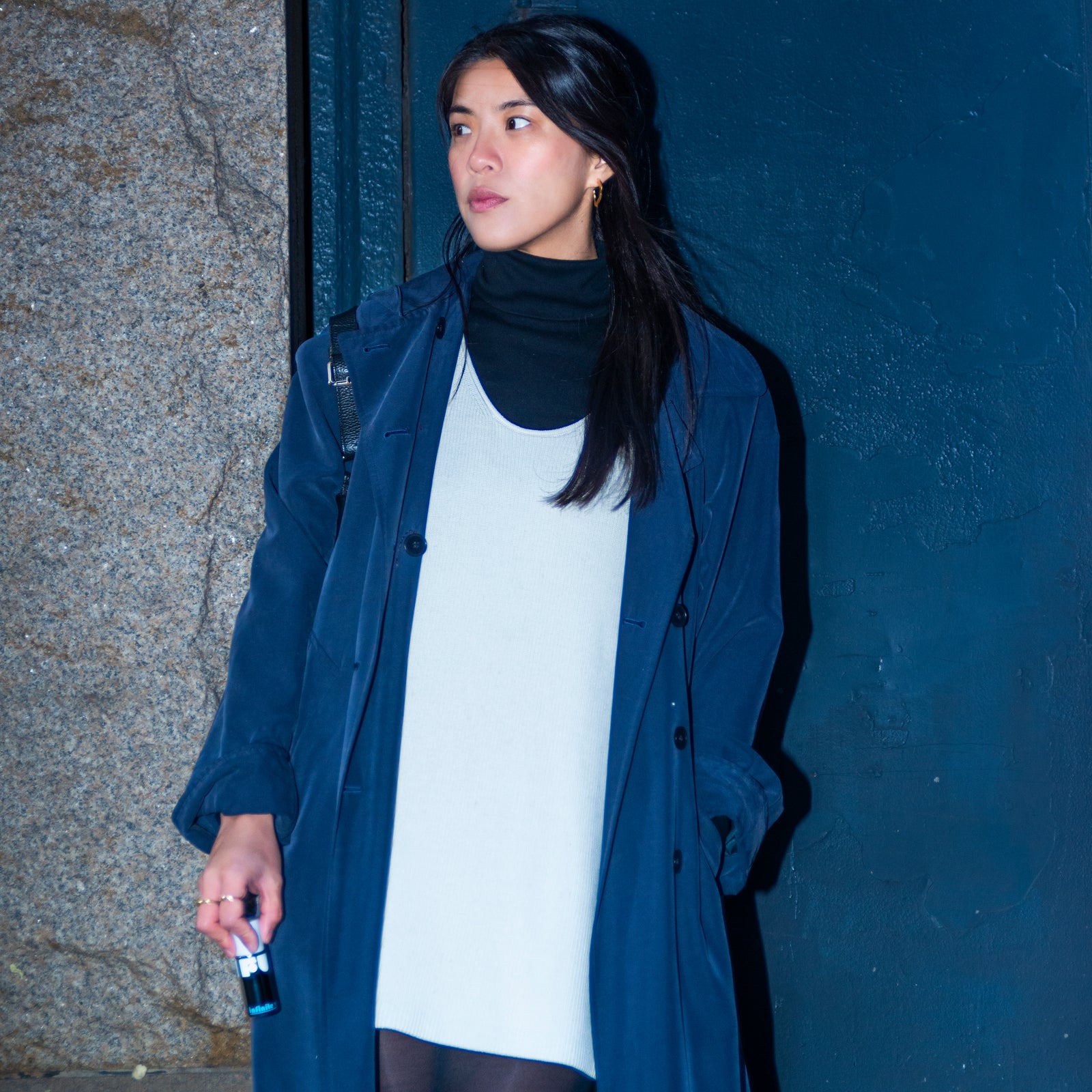 Woman wearing a blue coat against a dark wall